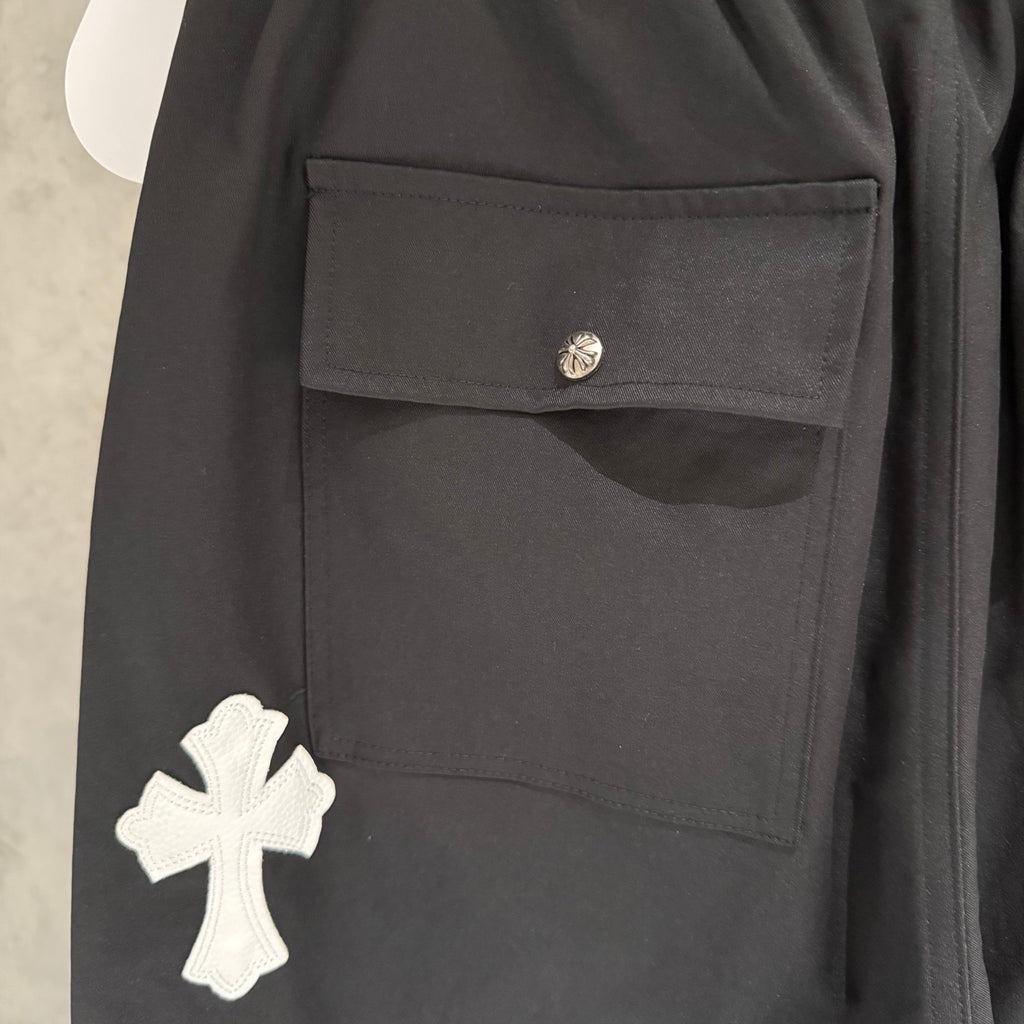 Black pants close-up showing side pocket flap and white cross applique.