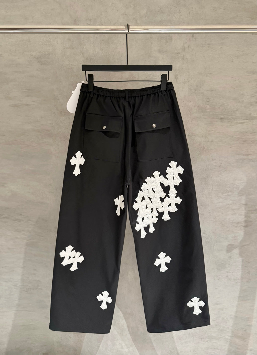 Black wide-leg pants with elastic waistband and white cross-shaped appliques.