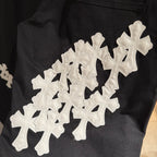 Black pants with large white cross applique graphic on the front leg.
