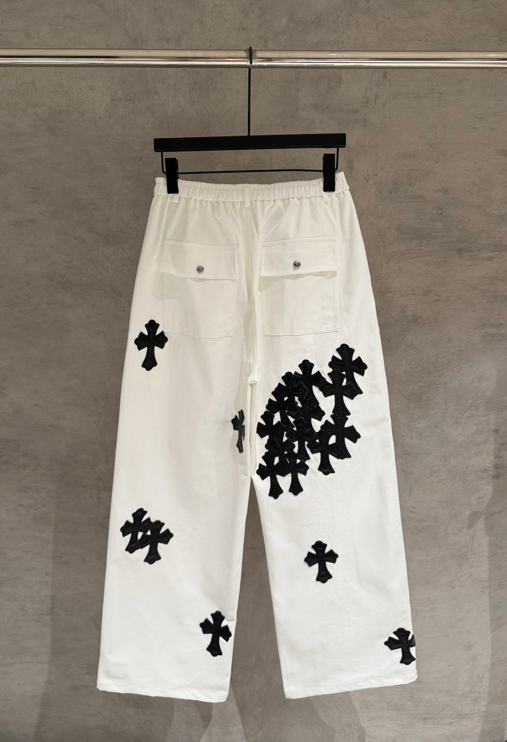 White wide-leg pants with black cross-pattern appliques