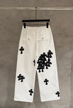 White wide-leg pants with black cross-pattern appliques