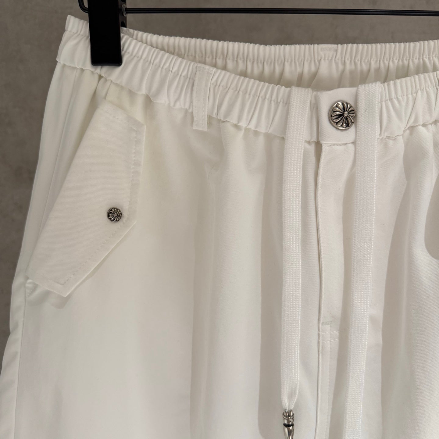 White pants close-up of elastic waistband, button detail, and side pocket