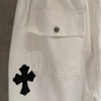 White pants with buttoned flap pocket and black cross applique
