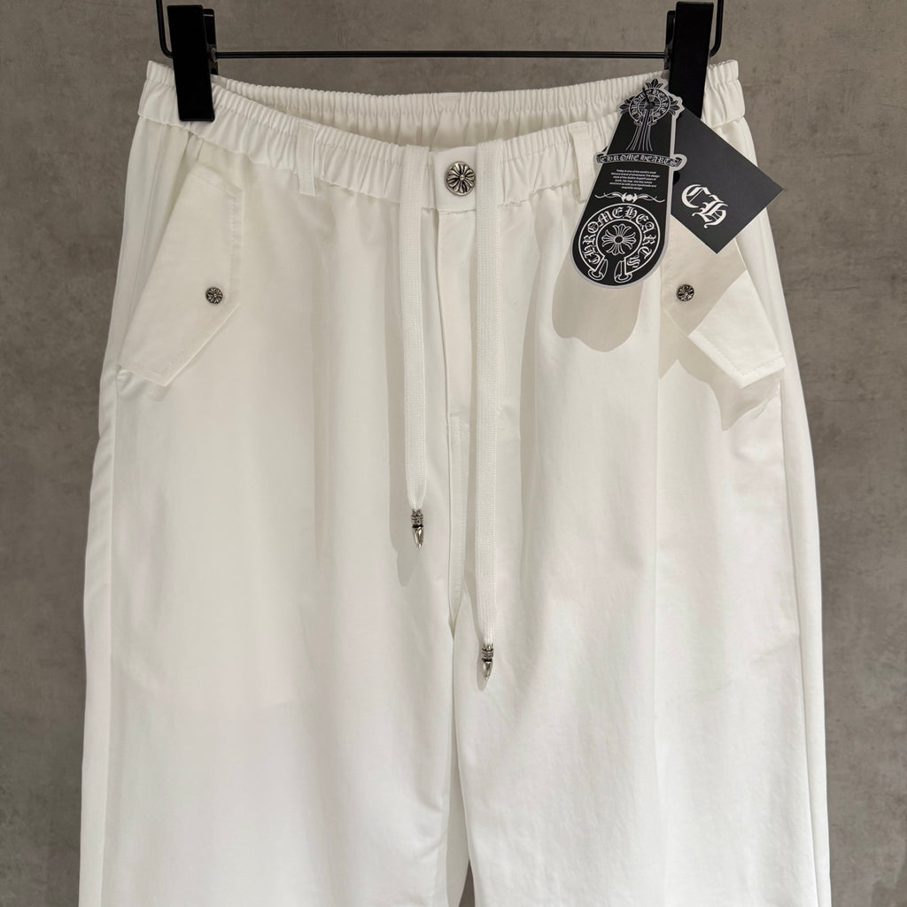 White drawstring pants with button front and decorative charm at the waistband