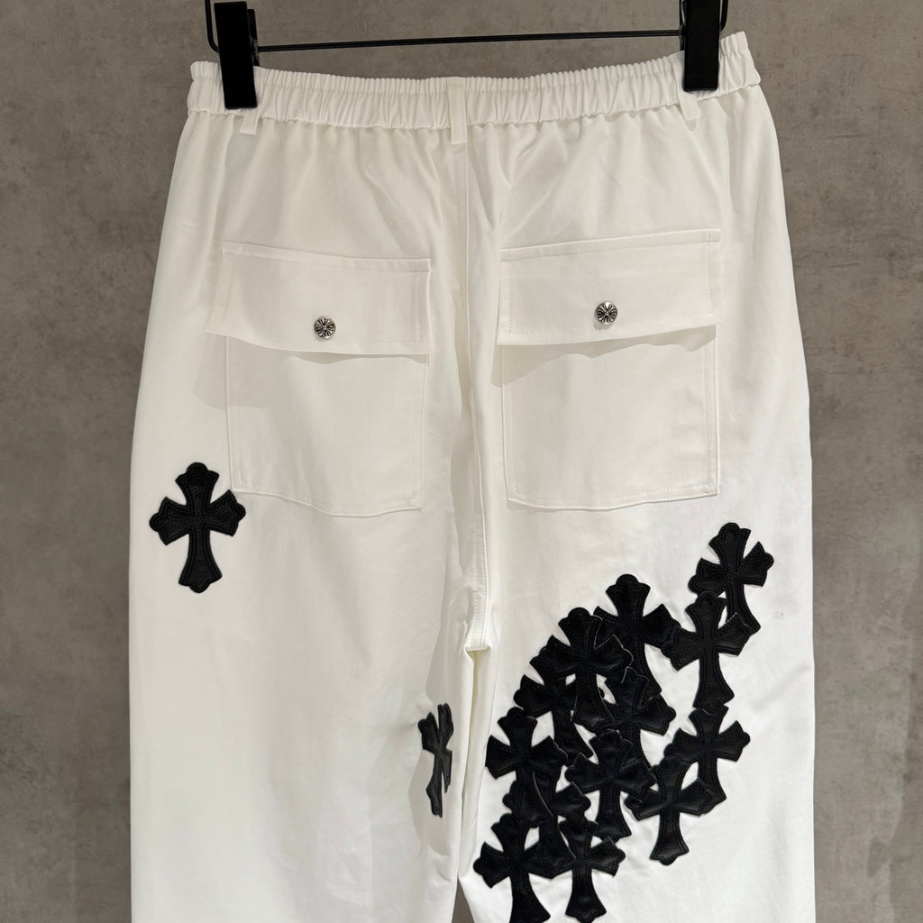 White wide-leg pants with black cross and cluster appliques