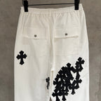 White wide-leg pants with black cross and cluster appliques