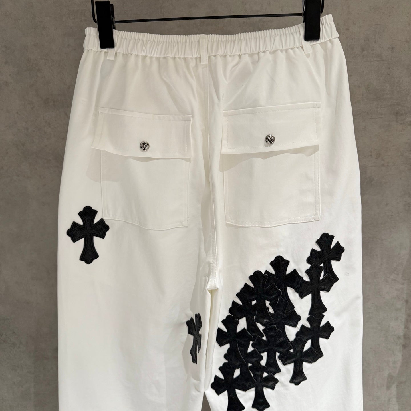 White wide-leg pants with black cross and cluster appliques