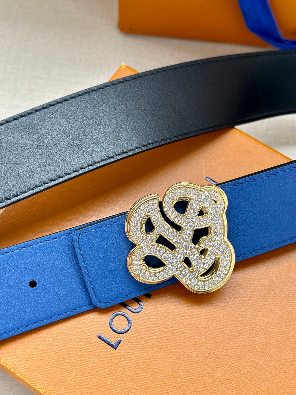 Louis Vuitton blue leather belt close-up with gold-tone logo buckle