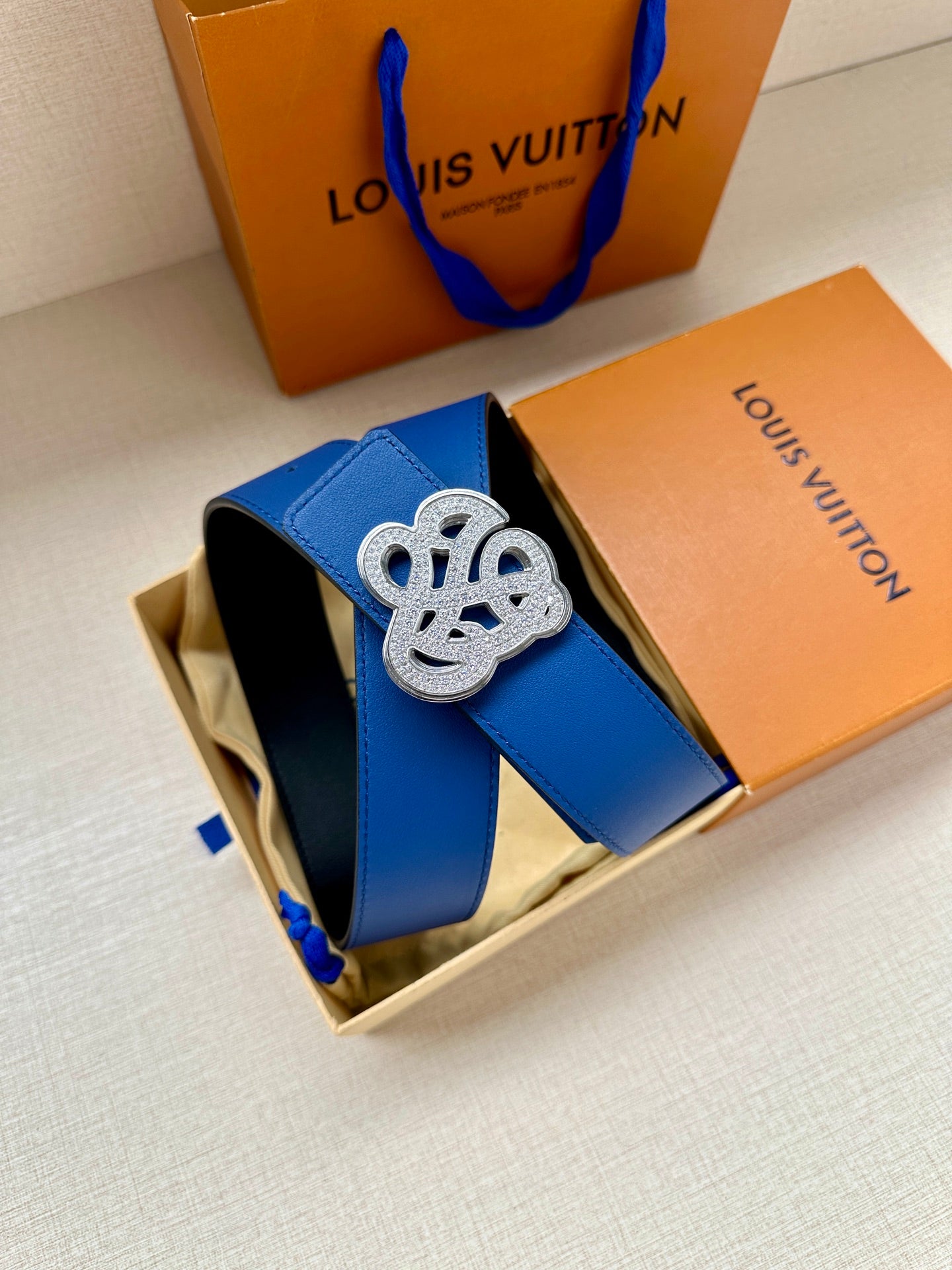 Louis Vuitton blue leather belt with gold-tone logo buckle, shown in box