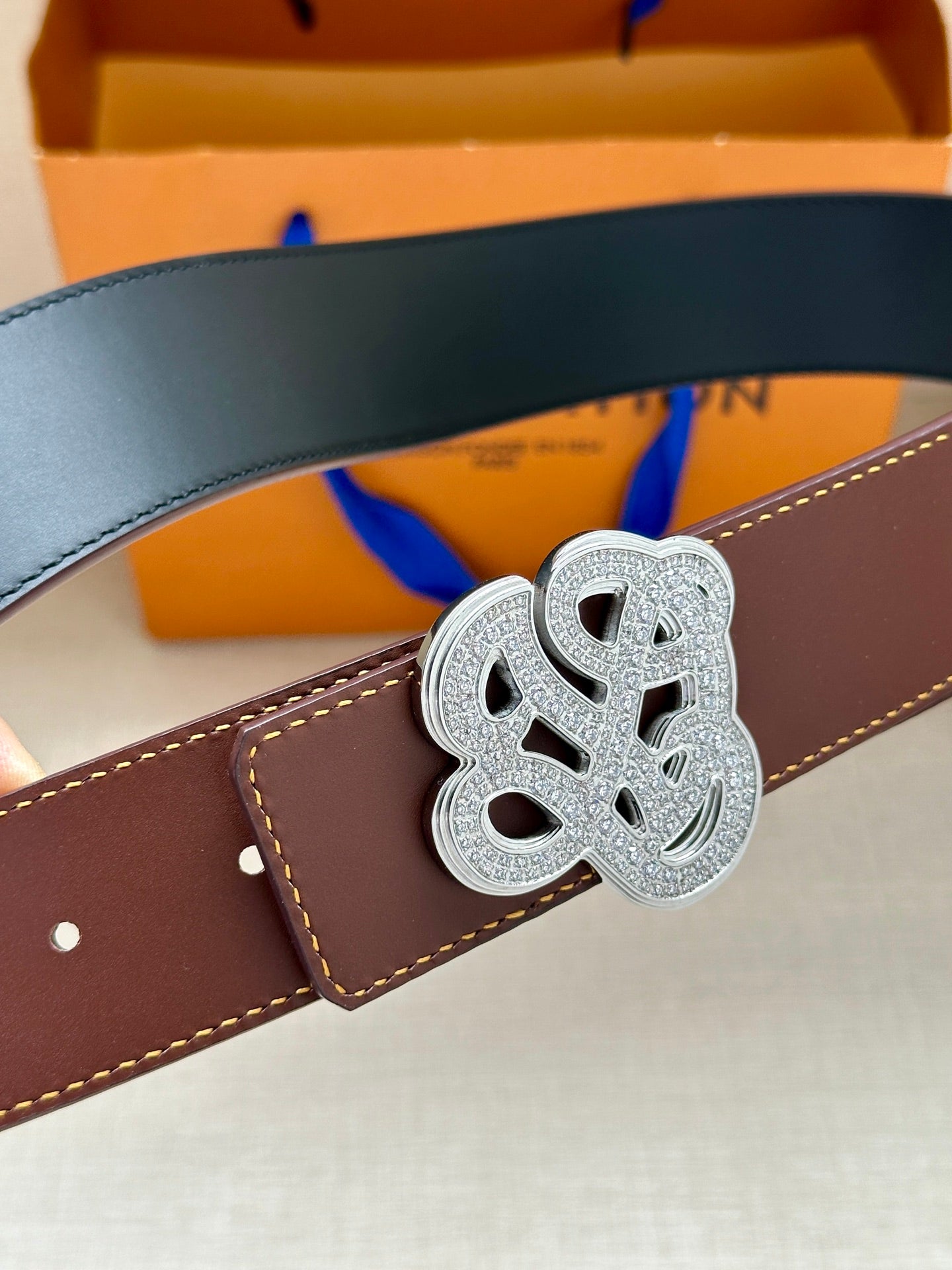 Brown leather belt with silver-tone logo buckle and stitched edge detail