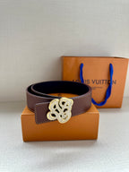 Brown leather belt with silver-tone logo buckle; underside shows dark navy
