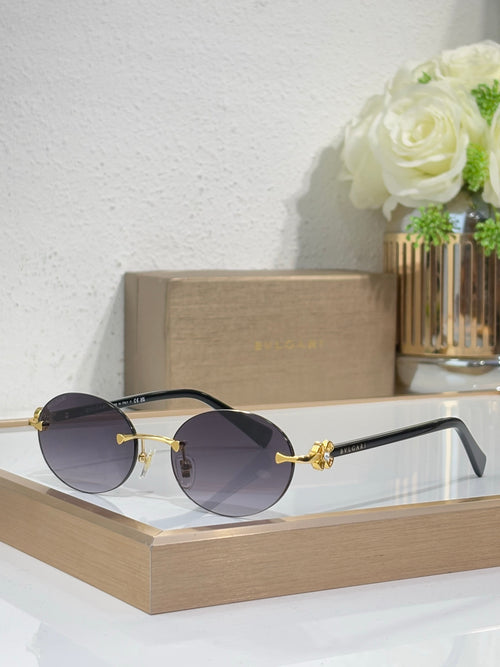 Gold-tone sunglasses with dark gray lenses and black temples, round lenses, jewel detail.