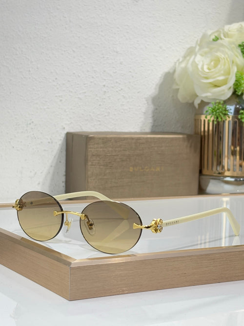Gold-tone sunglasses with dark gray lenses and white temples, round lenses, ornate hinge.
