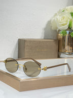 Gold-tone sunglasses with brown lenses and brown temples, round lenses, ornate central detail.
