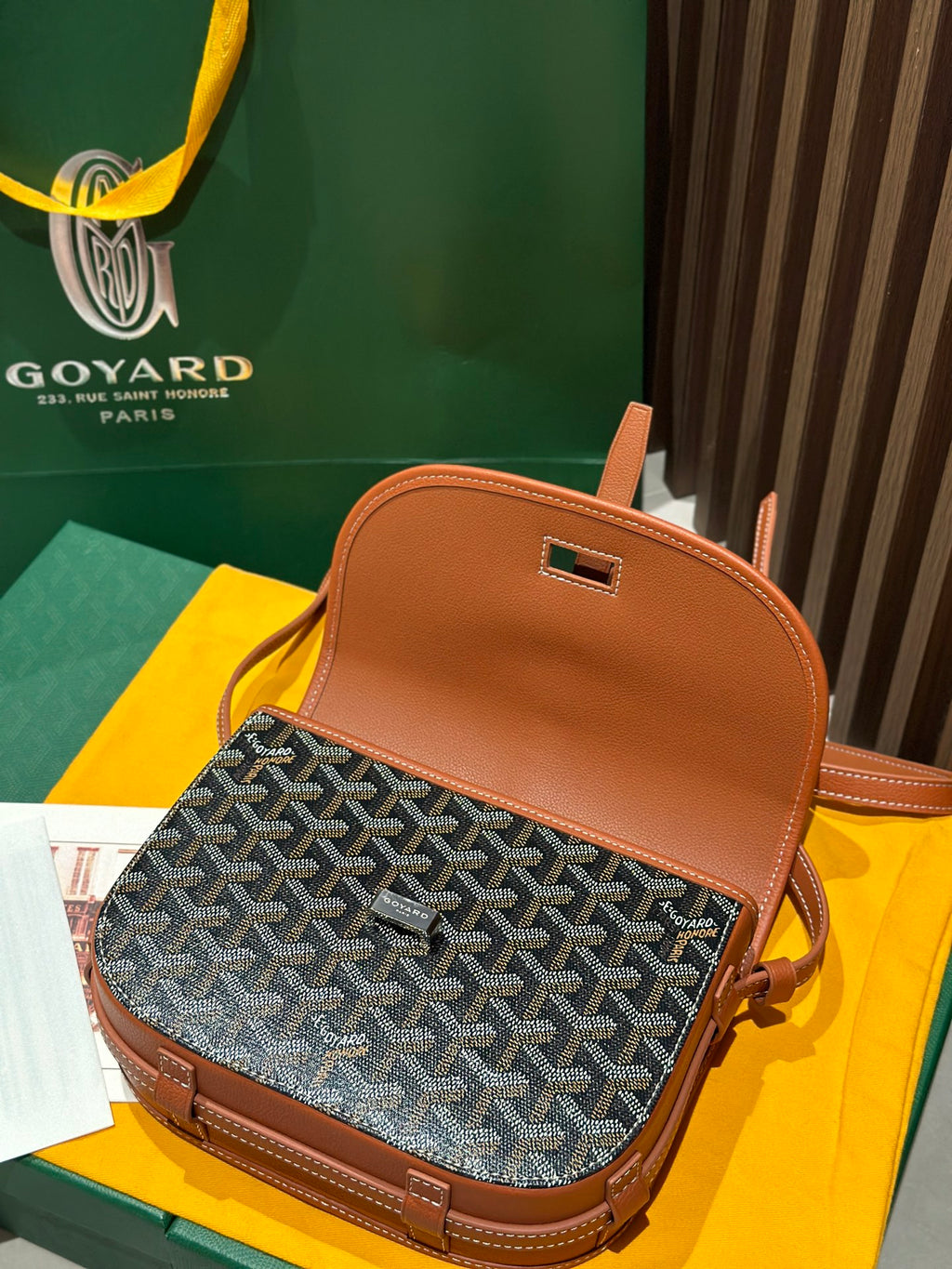Goyard mini bag with tan top handle, gray patterned front and tan flap.
