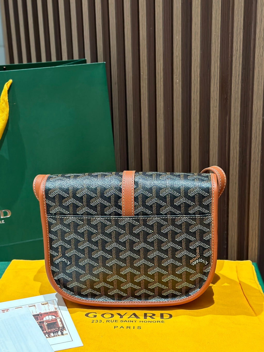 Goyard crossbody bag with gray geometric canvas, tan leather flap and shoulder strap.