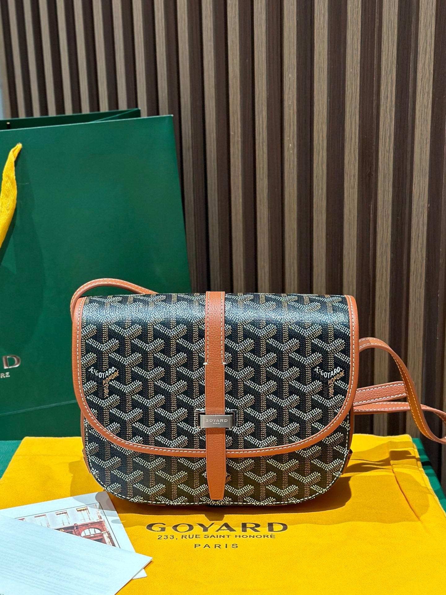 Goyard crossbody bag with geometric gray pattern, tan leather flap and strap.
