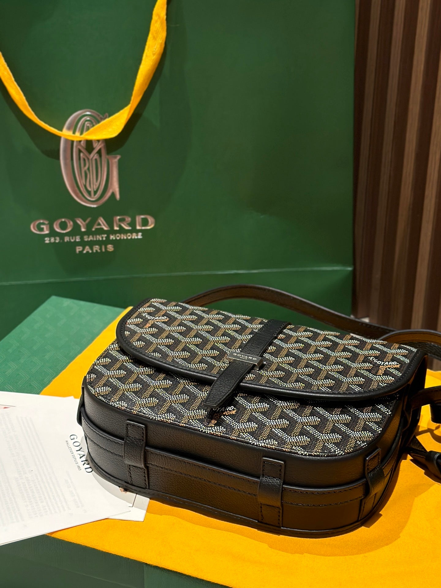 Goyard crossbody bag on display, patterned canvas top flap with black leather front