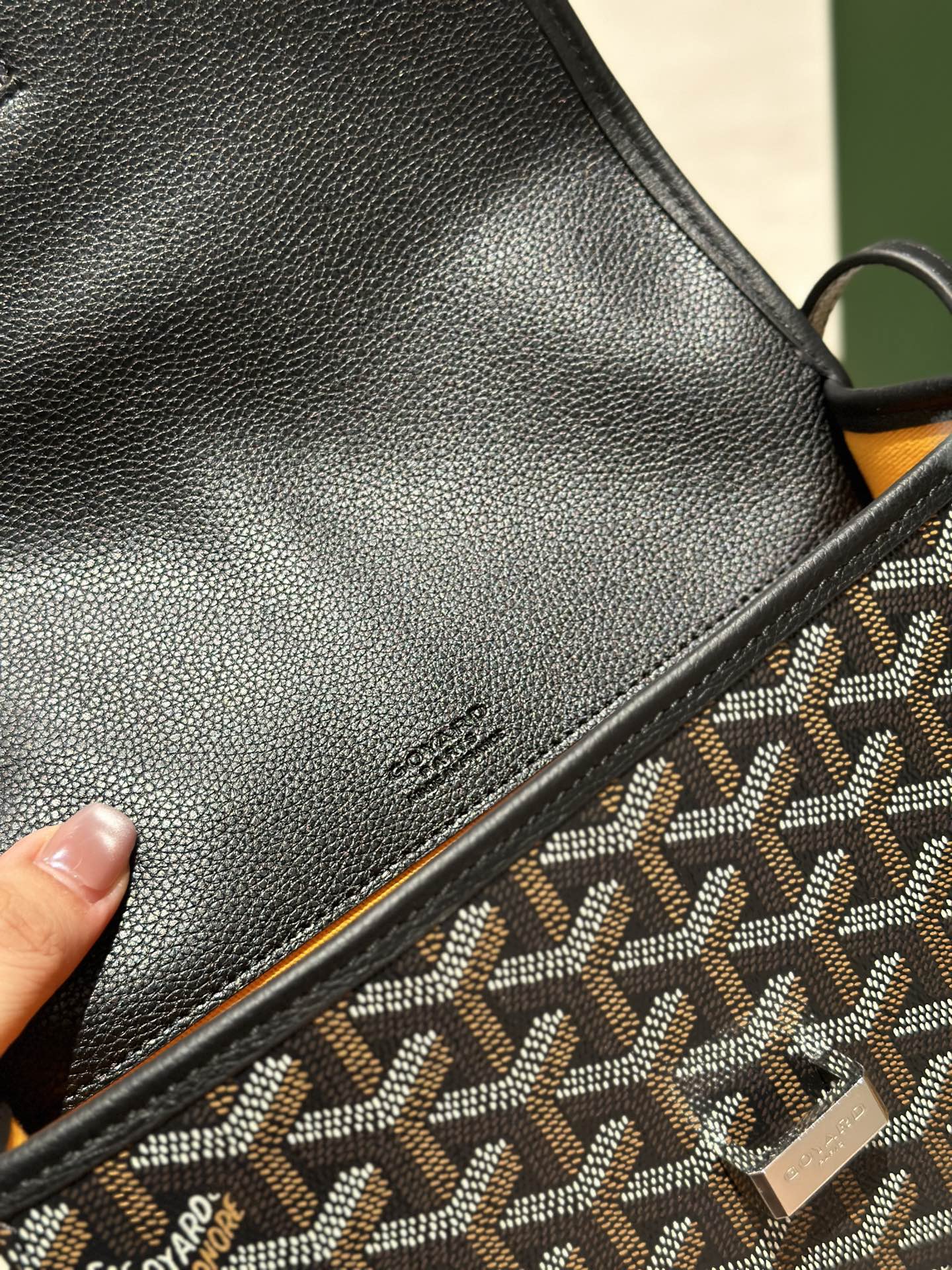 Goyard crossbody bag close-up of smooth black leather panel and patterned strap edge