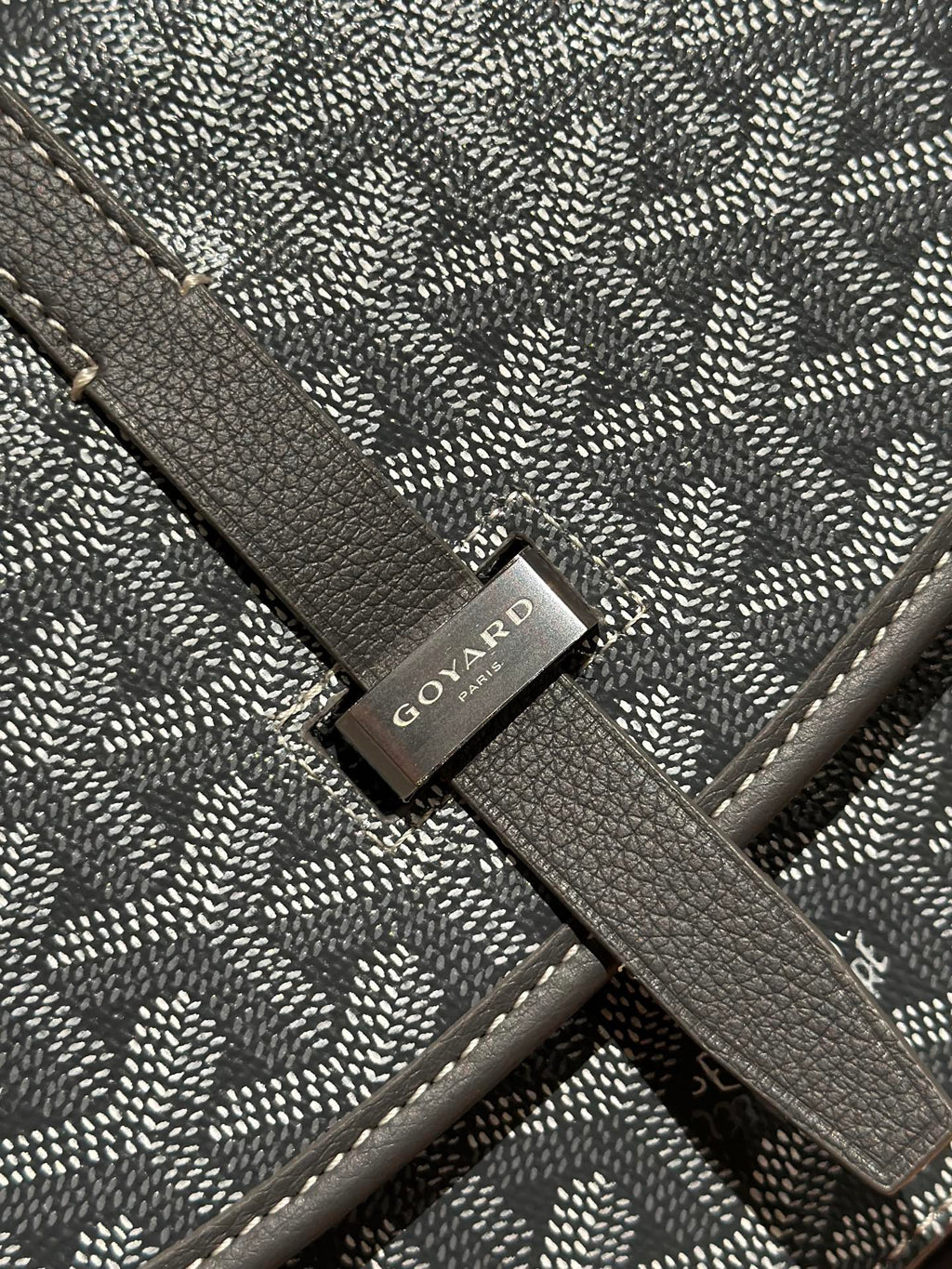 Goyard bag close-up of logo tag on patterned flap strap