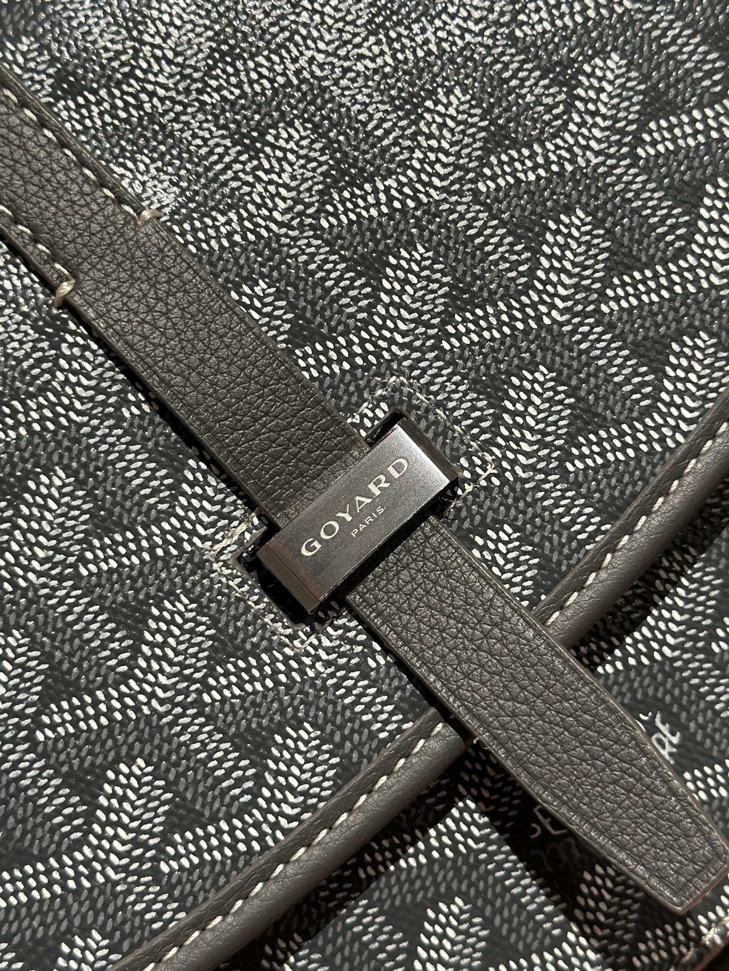 Goyard bag close-up of logo tag on patterned flap strap
