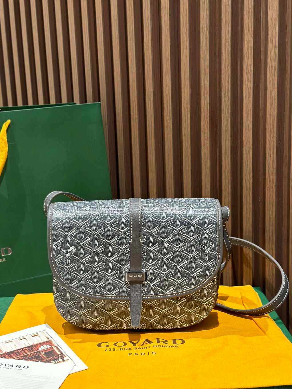 Goyard crossbody bag with patterned flap, brown trim, and adjustable shoulder strap