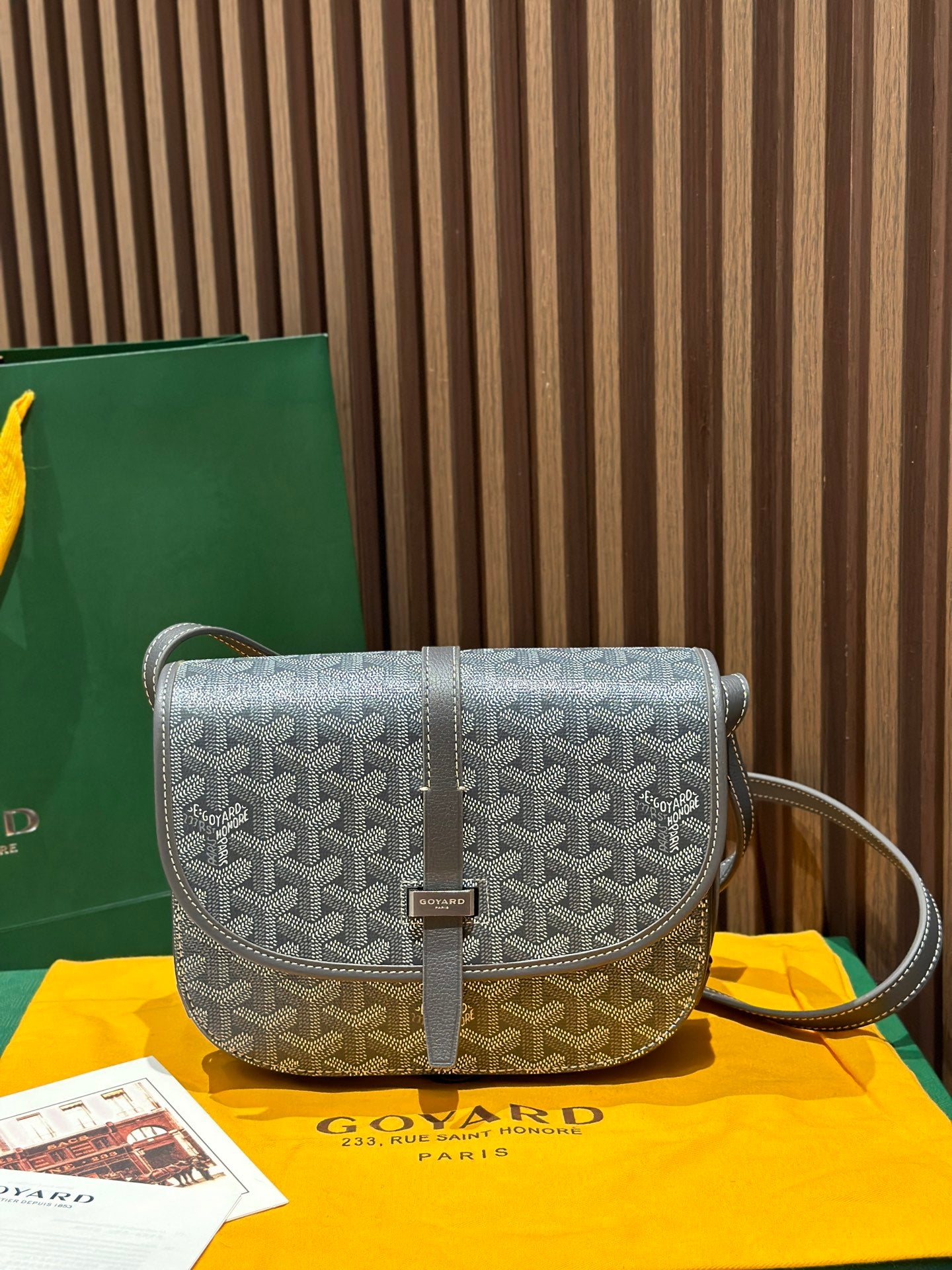Goyard crossbody bag with patterned flap, brown trim, and adjustable shoulder strap