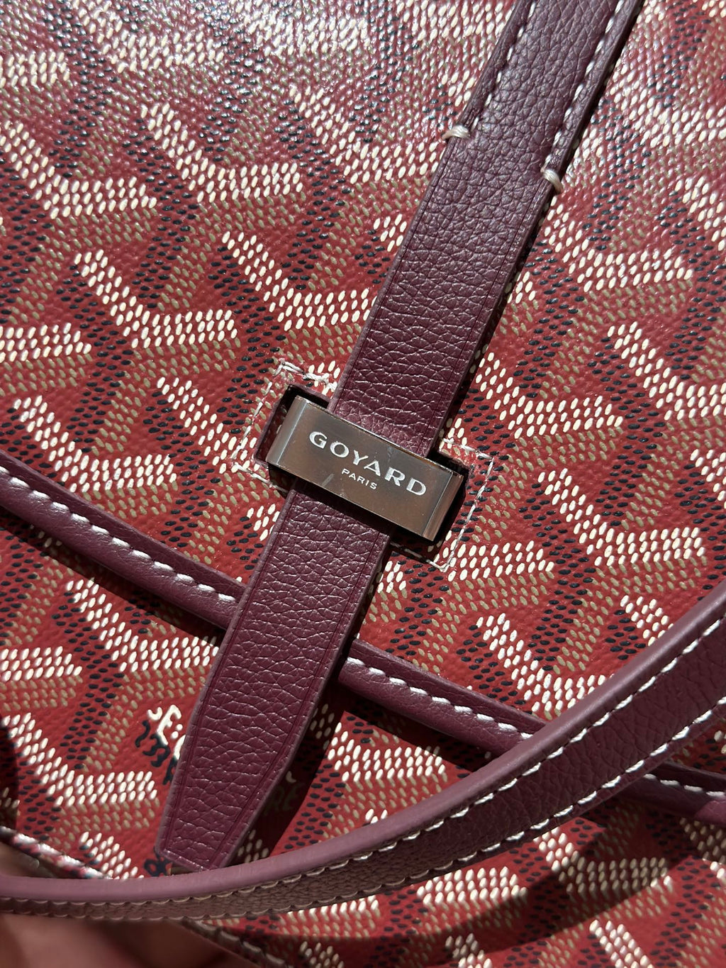 Goyard flap closure hardware with Goyard logo on maroon leather and patterned canvas