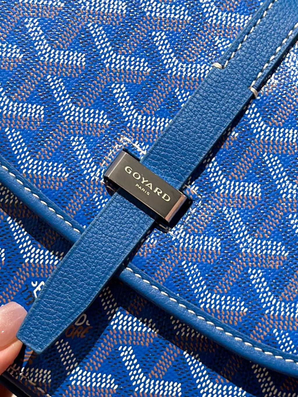 Goyard bag logo hardware on blue leather strap over monogram fabric