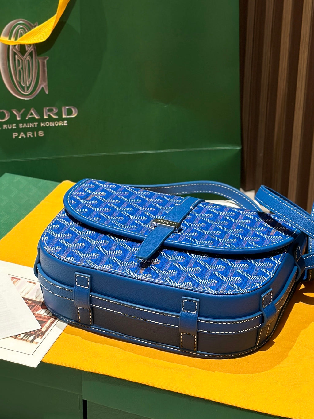 Goyard bag with blue monogram fabric flap, top handle, and contrast leather accents