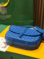 Goyard bag with blue monogram fabric flap, top handle, and contrast leather accents