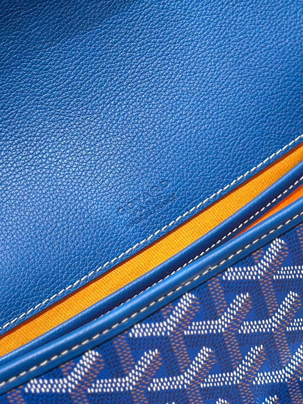 Blue leather trim and monogram fabric detail on a Goyard bag