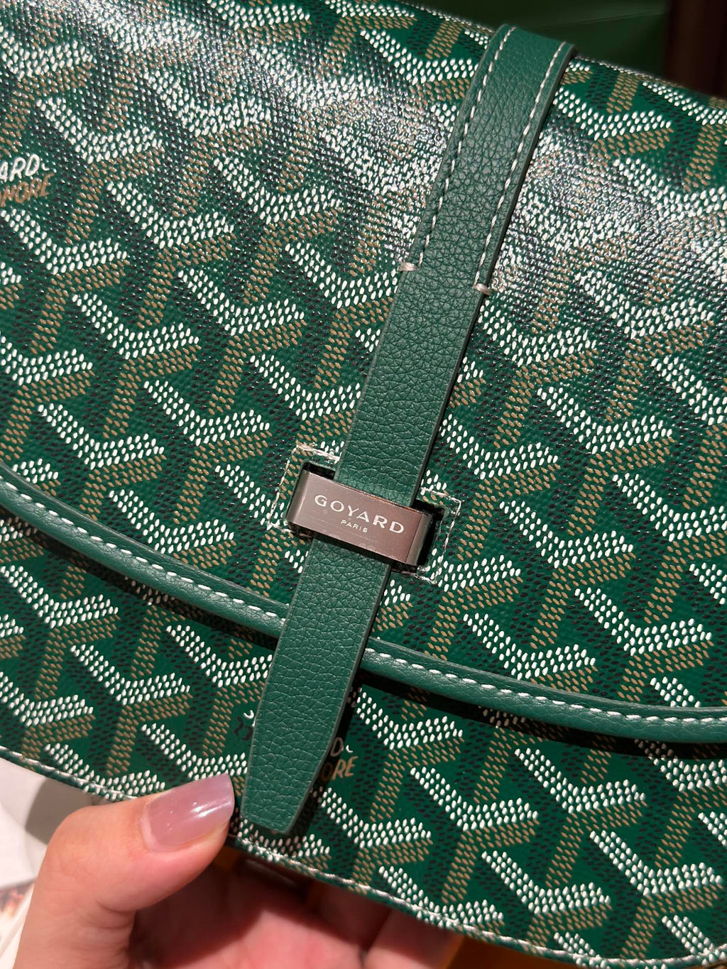 Goyard patterned flap crossbody bag closeup with logo patch and green leather trim