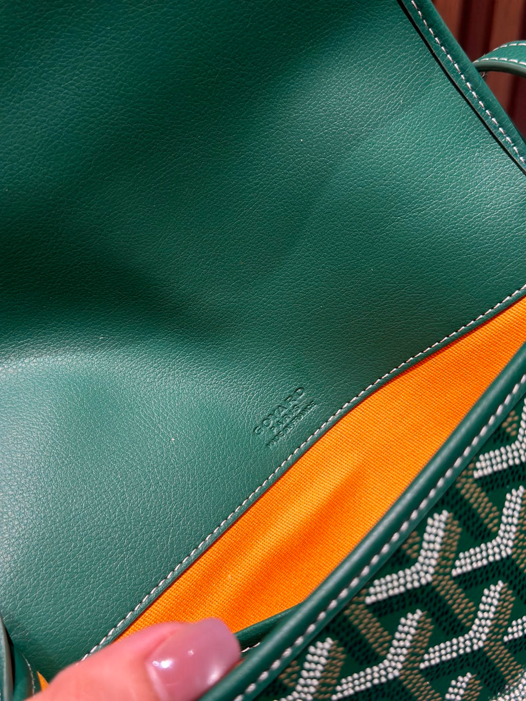 Goyard green leather trim closeup with visible stitching and small logo stamp