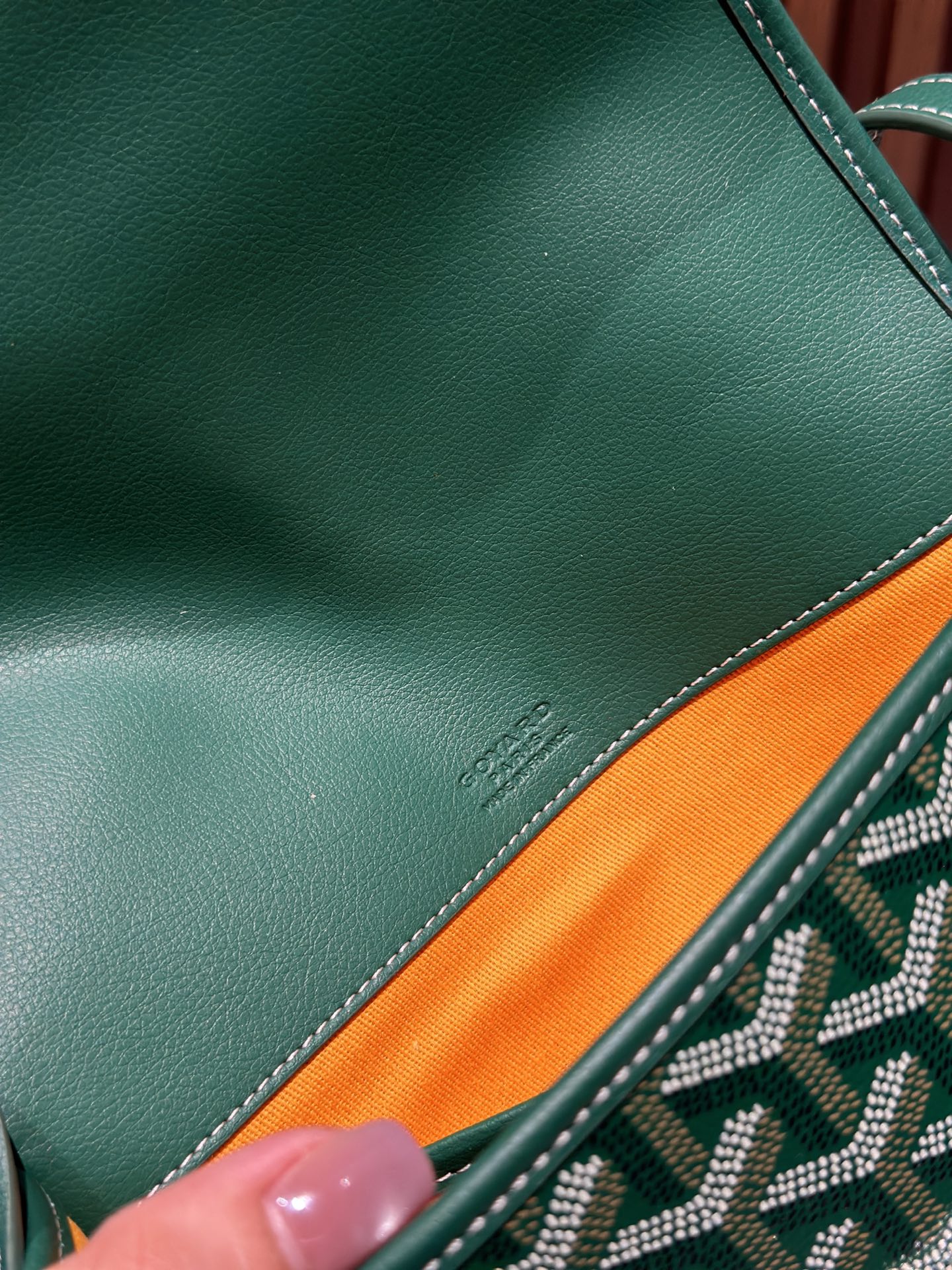 Goyard green leather trim closeup with visible stitching and small logo stamp