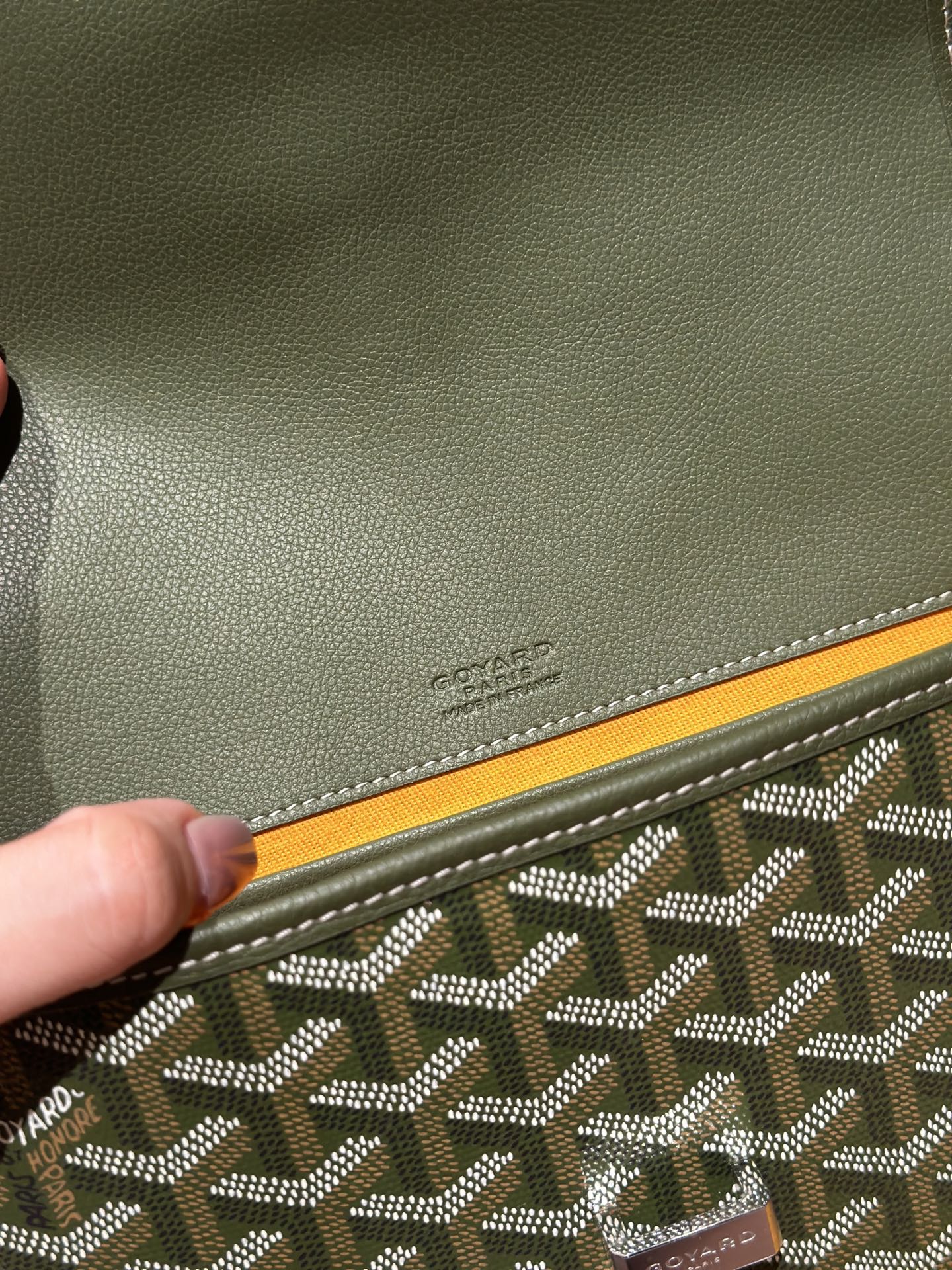 Embossed Goyard logo on olive leather corner trim with patterned canvas edge.
