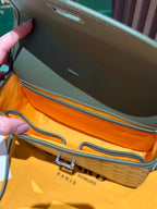 Interior view of green leather crossbody bag opening with stitching and strap detail.