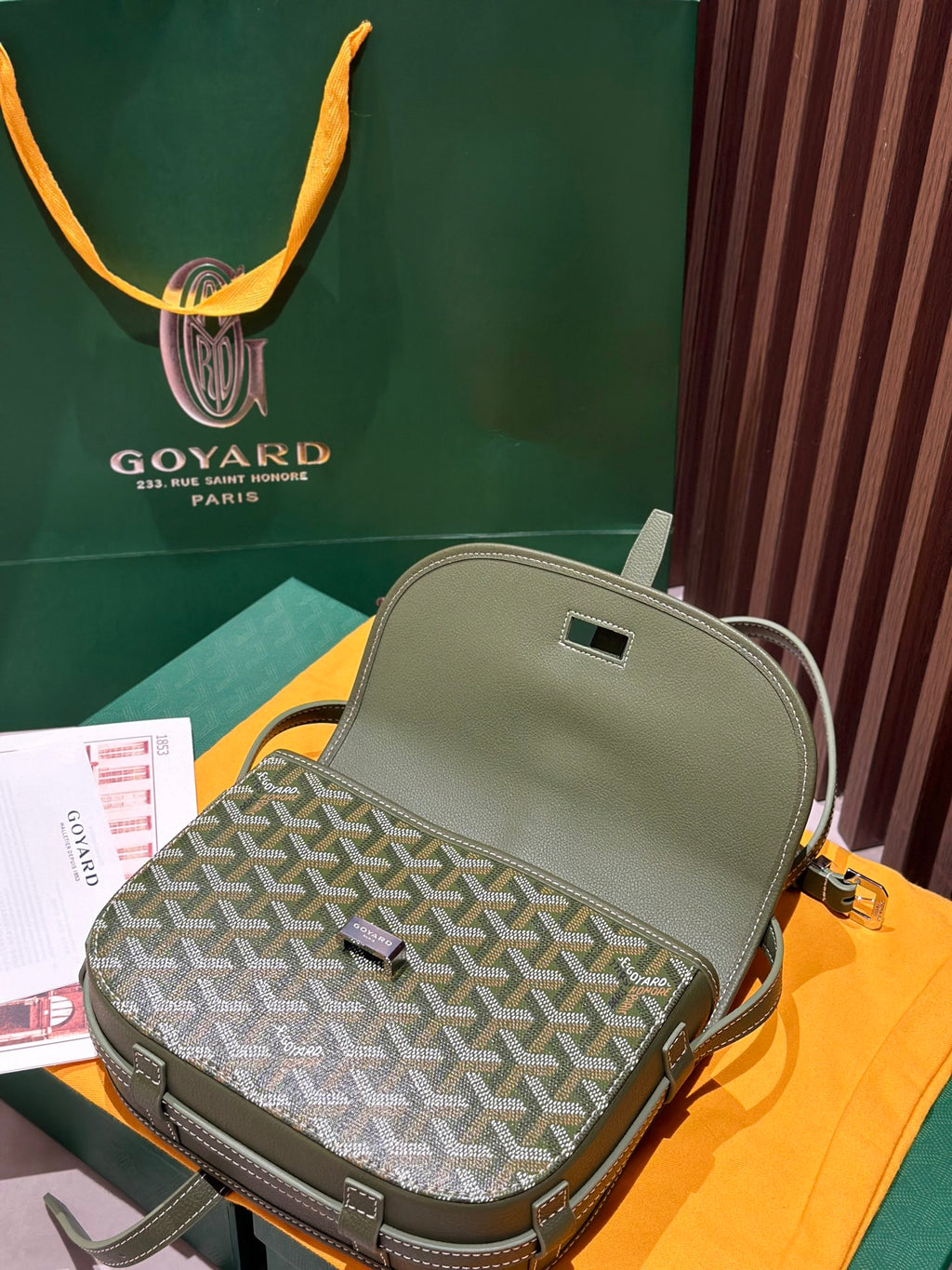 Green leather back of a small crossbody bag with Goyardine patterned flap and strap.