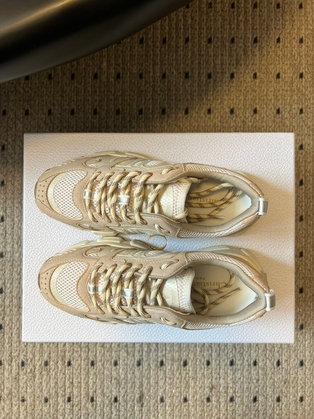 Dior unisex sneakers close-up, cream uppers with metallic gold lace detail