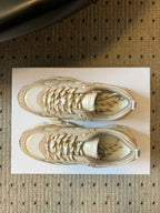 Dior unisex sneakers close-up, cream uppers with metallic gold lace detail