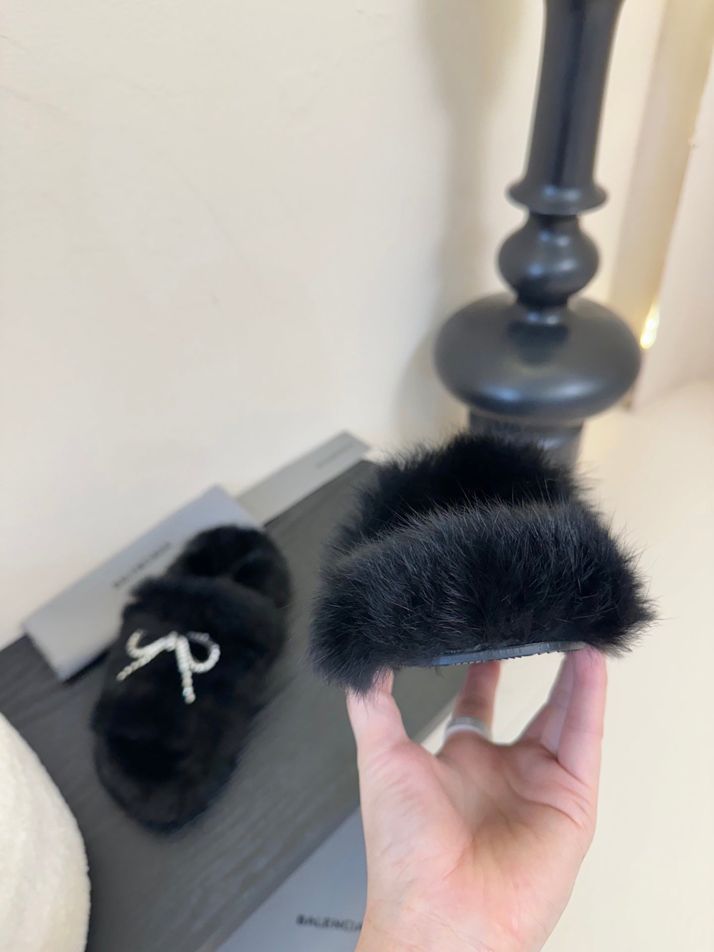 Balenciaga black plush slide sandals, hand holds one with rhinestone bow