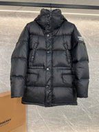 Dark long puffer jacket with hood, button front and flap pockets (sleeve patch visible)