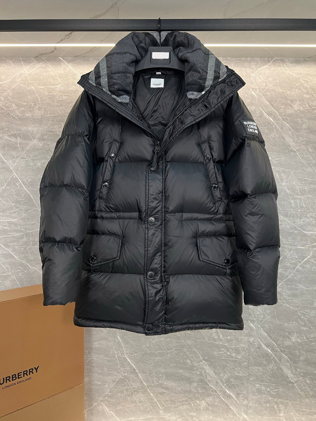 Dark long puffer jacket with hood and button front, open collar detail