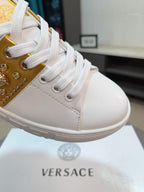 White low-top sneakers with gold studded side panel and lace-up front