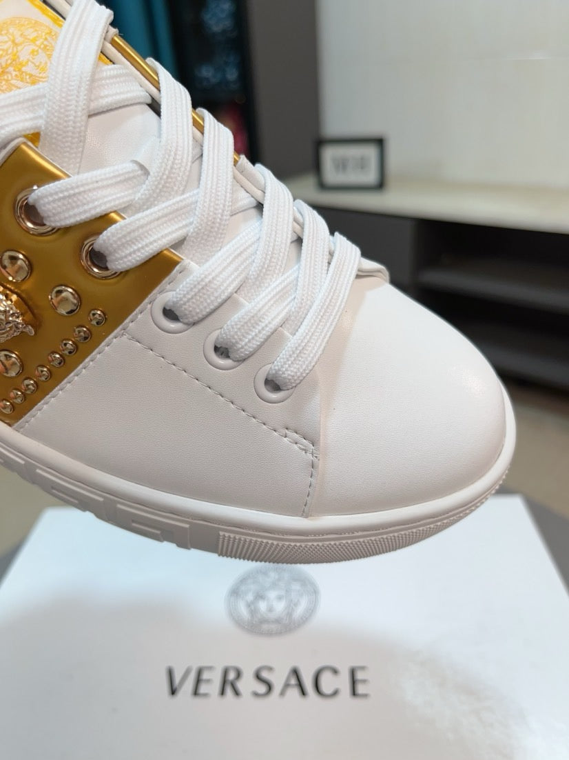 White low-top sneakers with gold studded side panel and lace-up front