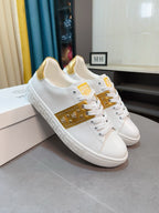 White and gold low-top sneakers with studded side stripe and lace-up