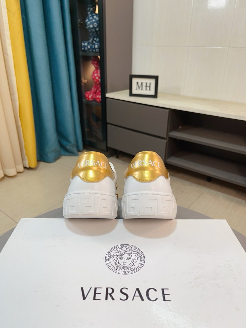 White low-top sneakers with gold heel tabs on rear view