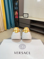 White low-top sneakers with gold heel tabs on rear view