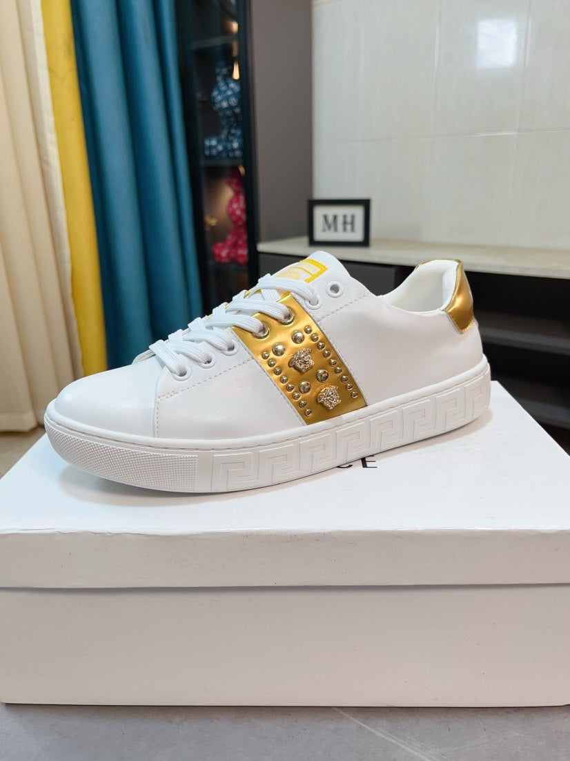 White low-top sneakers with gold studded stripe and patterned rubber sole