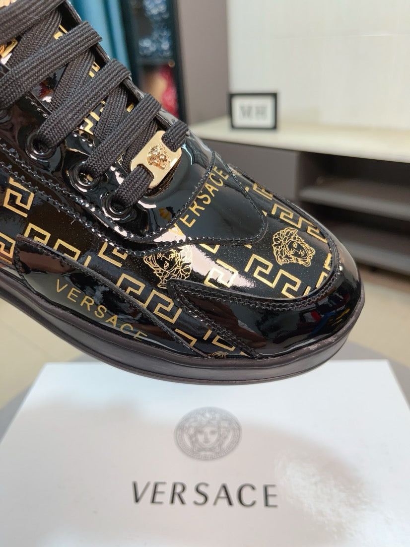 Black Versace sneakers with gold Greca pattern, lion charm, glossy toe cap and laces